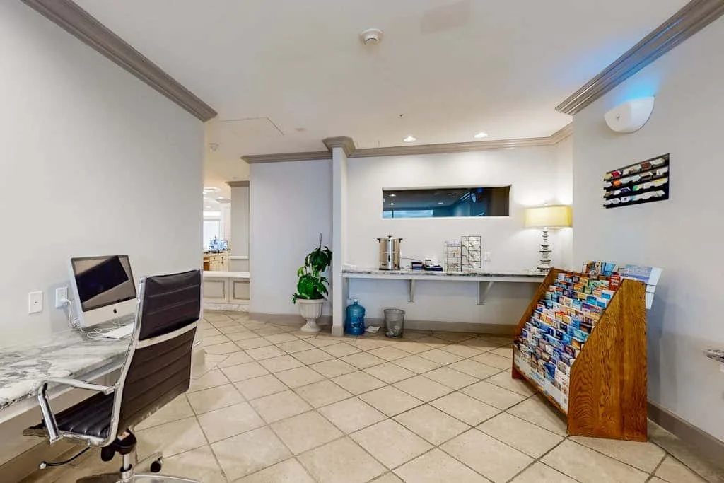 A bright tiled room with a counter, seating, and a wooden display rack.