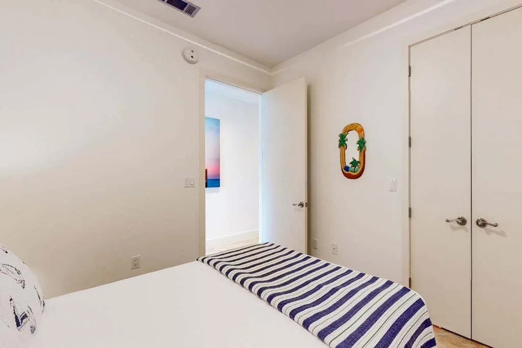 A bedroom with a bed covered by a striped blanket and an open doorway.