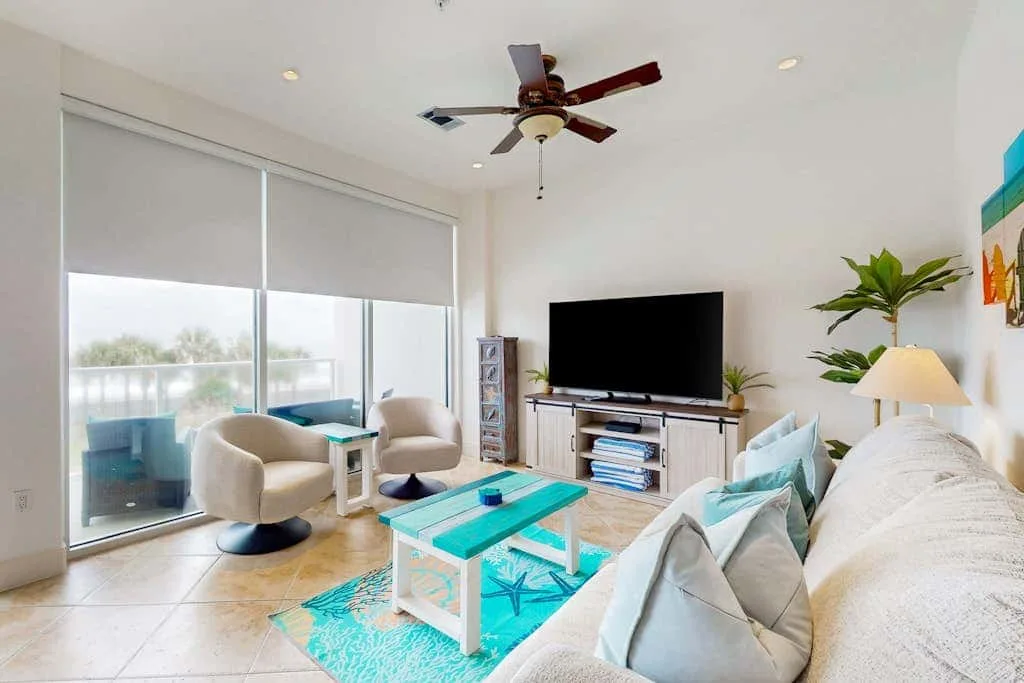 A bright living room with seating, a television, and sliding glass doors.