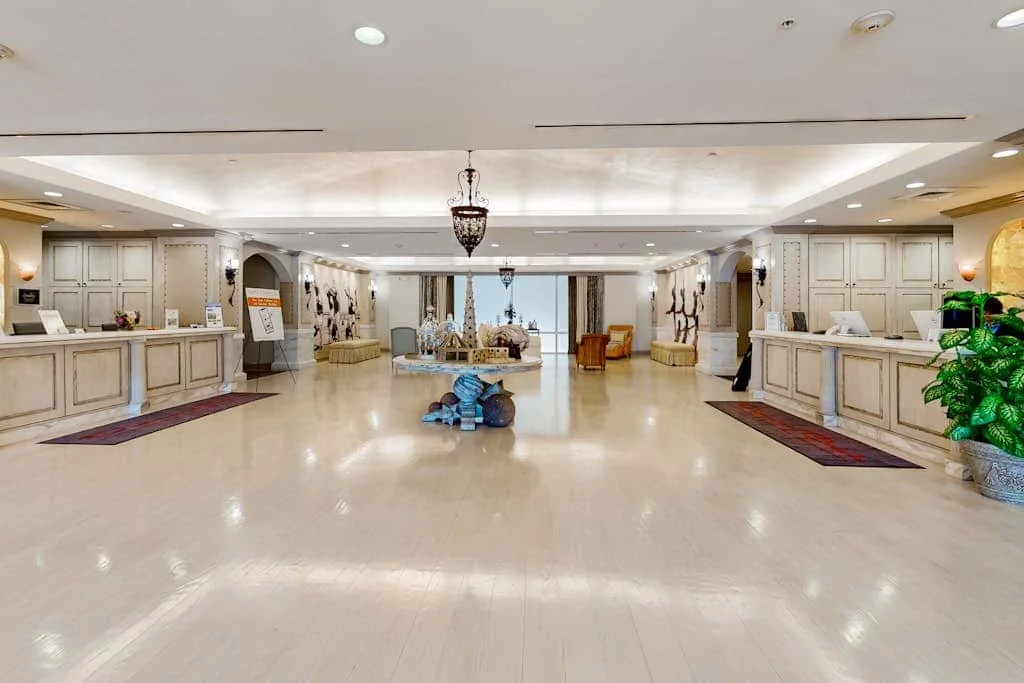 A spacious hotel lobby with reception desks on both sides and seating in the distance.