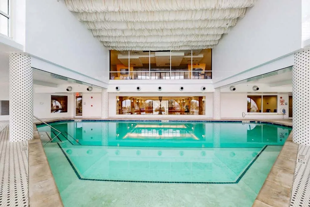 An indoor swimming pool with a glass-fronted room overlooking the water.