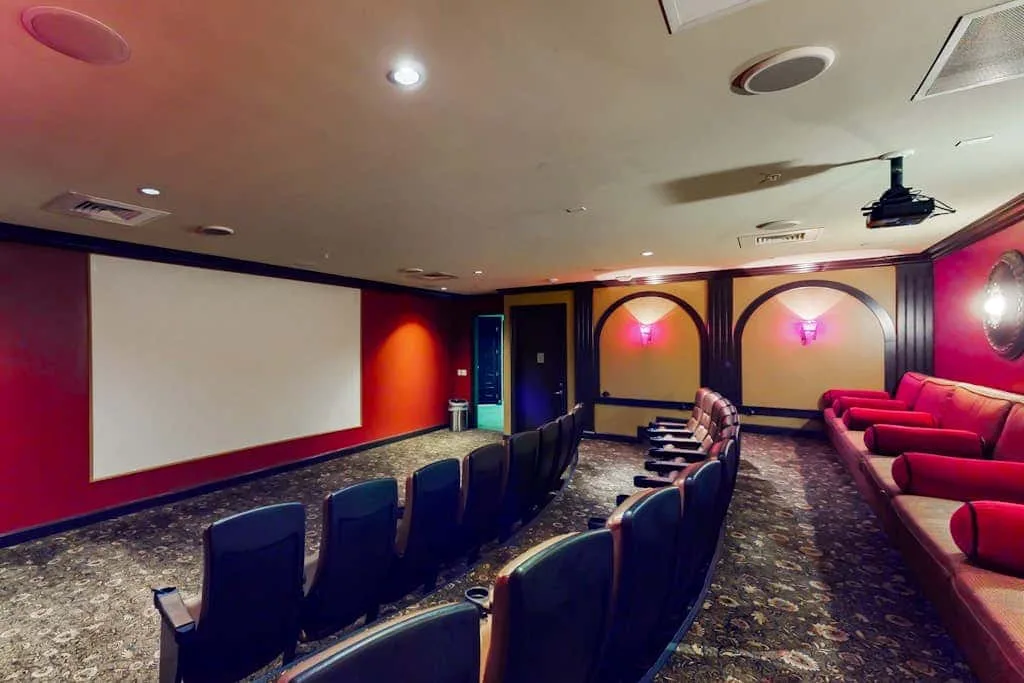 A small screening room has rows of seating facing a large projection screen.
