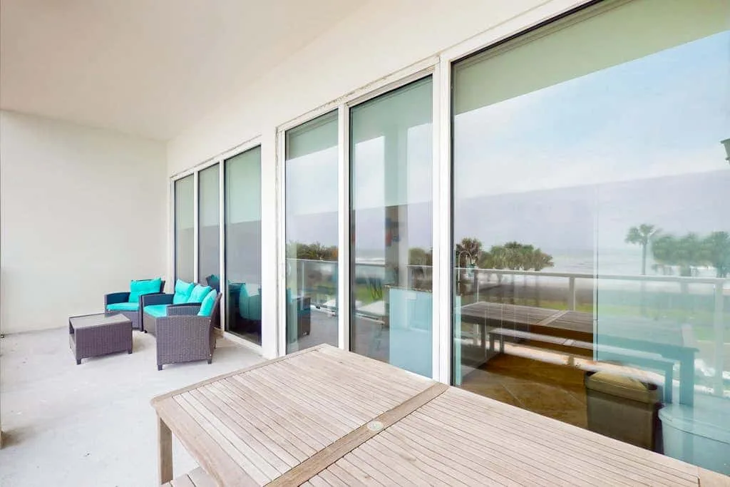 A covered terrace with outdoor seating and a wooden table overlooks the water.