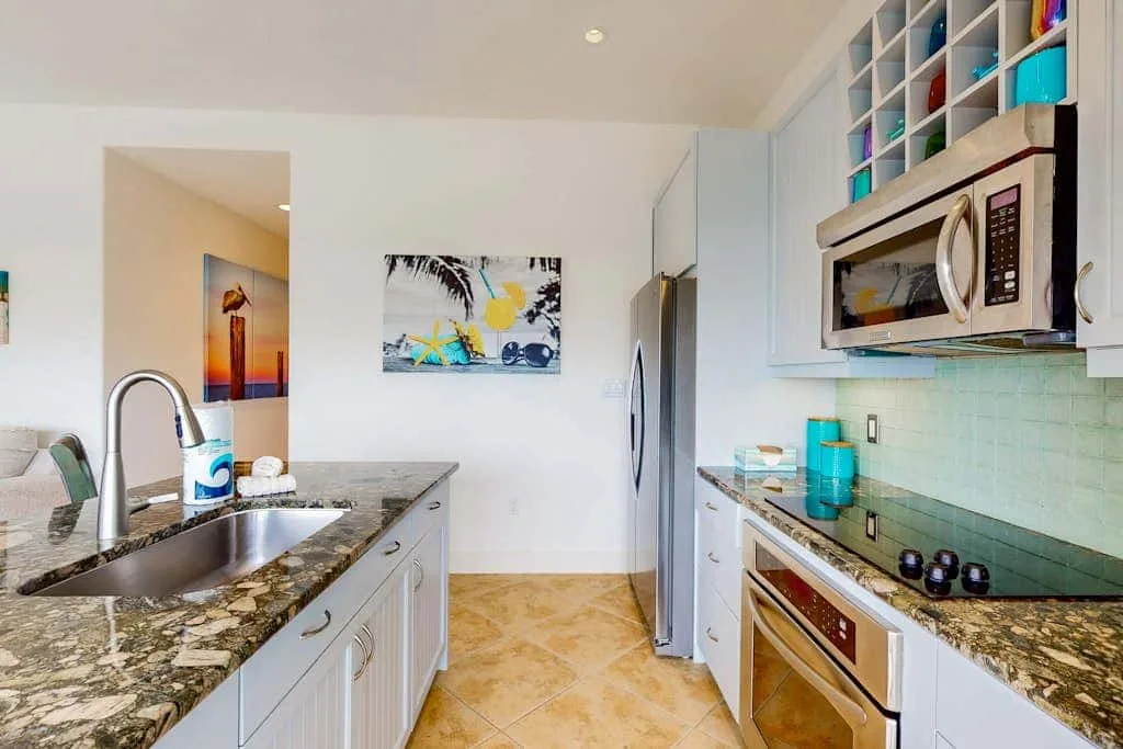 A bright kitchen with countertops, a sink, and stainless steel appliances.