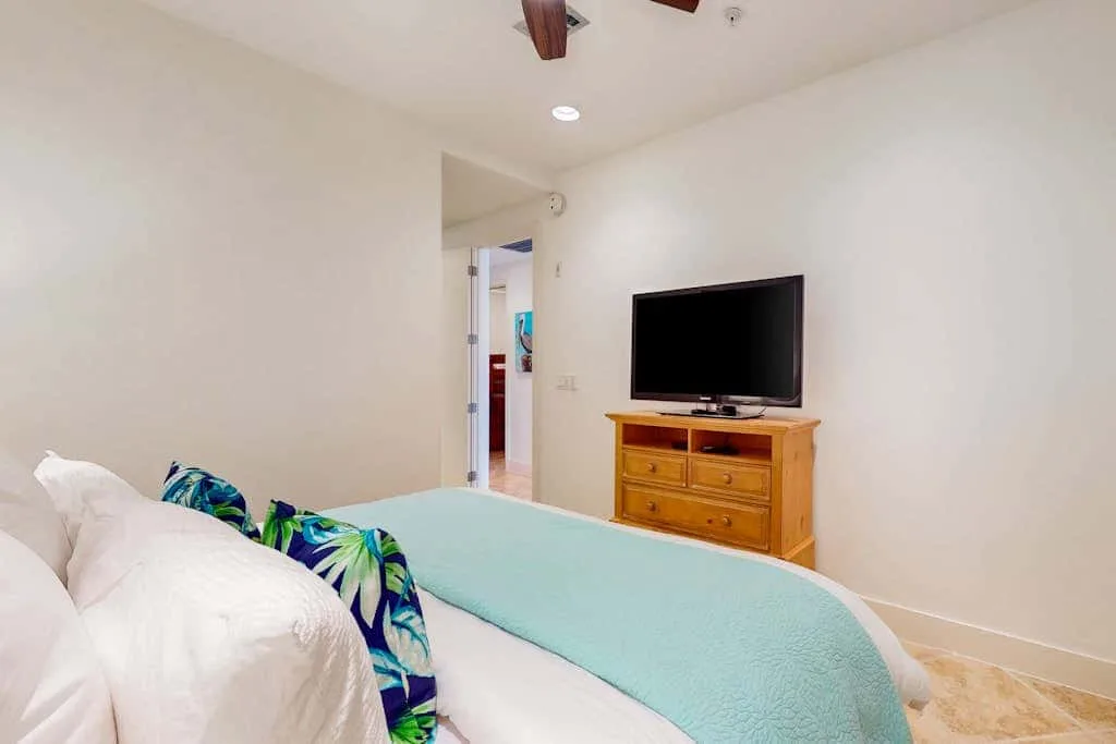 A bedroom with a bed and television on a wooden dresser.