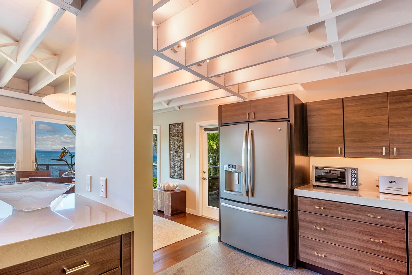Una cocina abierta con gabinetes de madera oscura y un refrigerador de acero inoxidable.