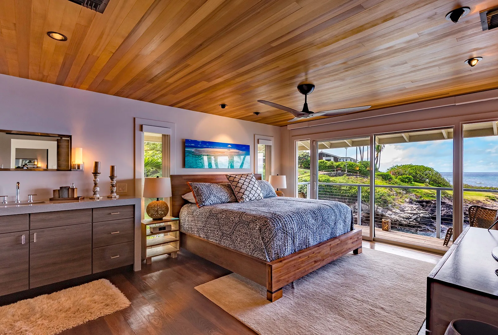 Un dormitorio con una cama de madera junto a grandes puertas de vidrio que dan a un jardín.