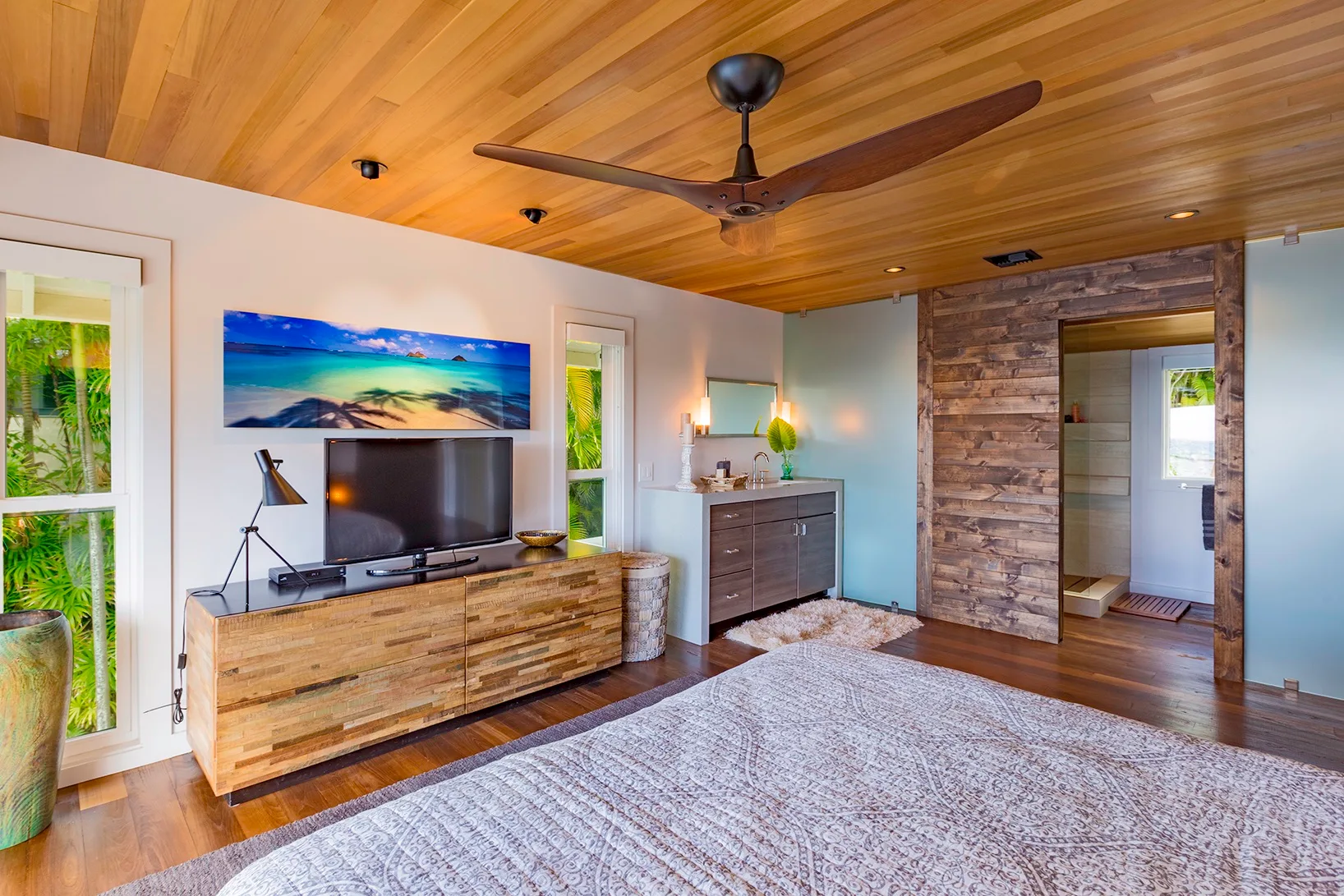 Una sala de estar con televisor, mueble de madera y ventilador de techo.