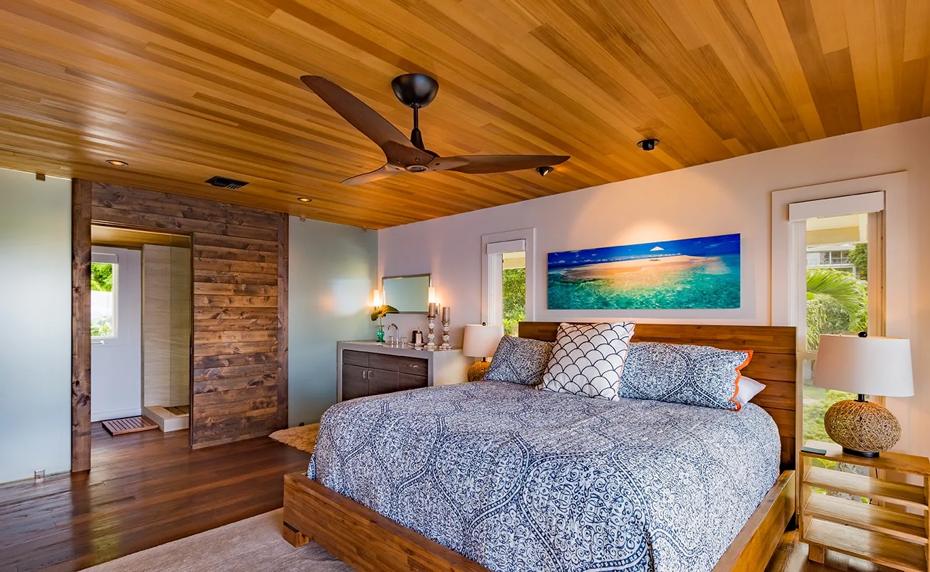 Un dormitorio con una cama grande, techo revestido de madera y arte del océano.