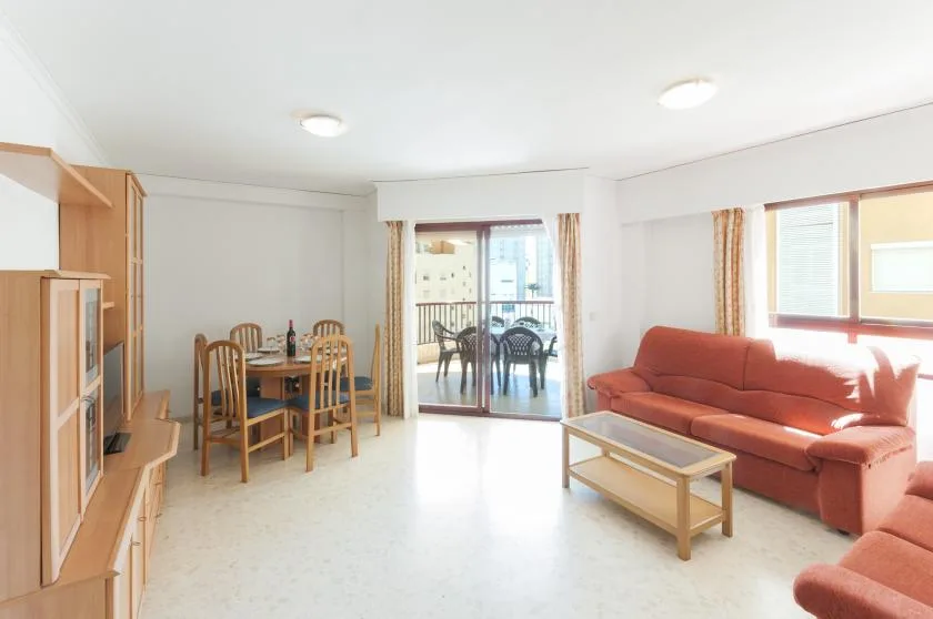 A bright living and dining area with seating, a dining table, and sliding glass doors.