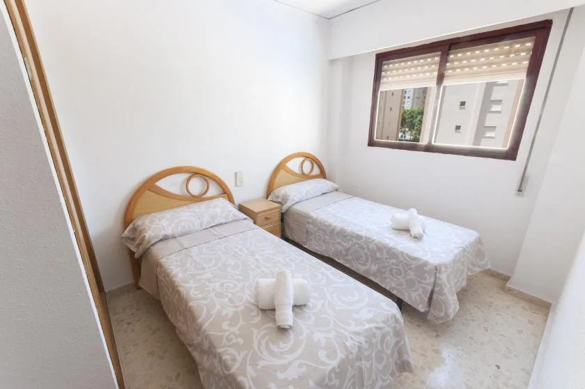 A twin bedroom with two single beds and a window.