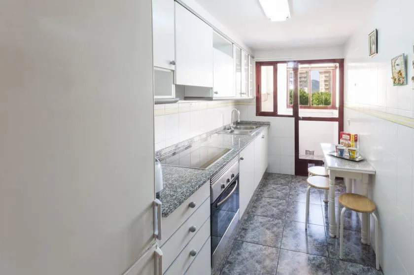 A narrow kitchen with a countertop, cabinets, and a small dining table.