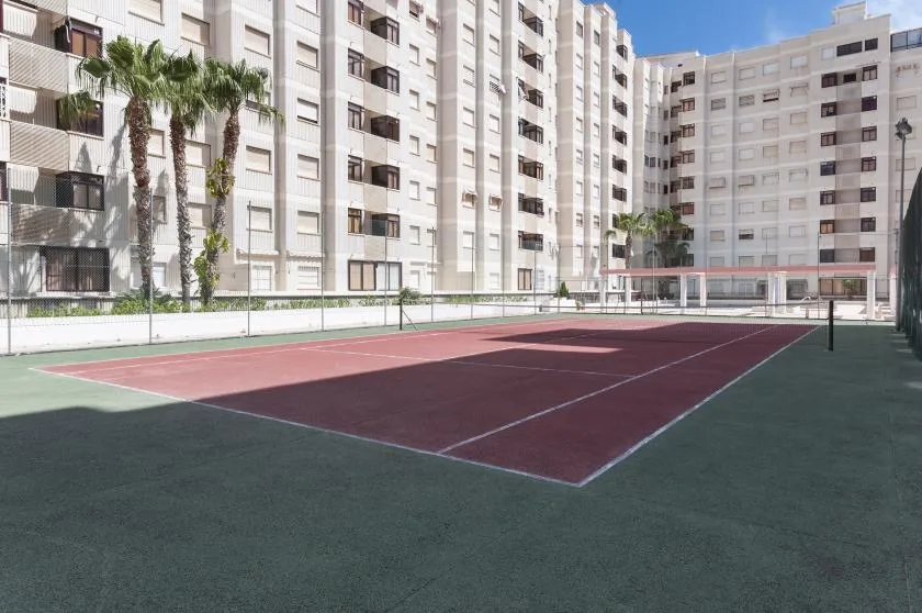 An outdoor court with painted playing lines sits among tall apartment buildings.