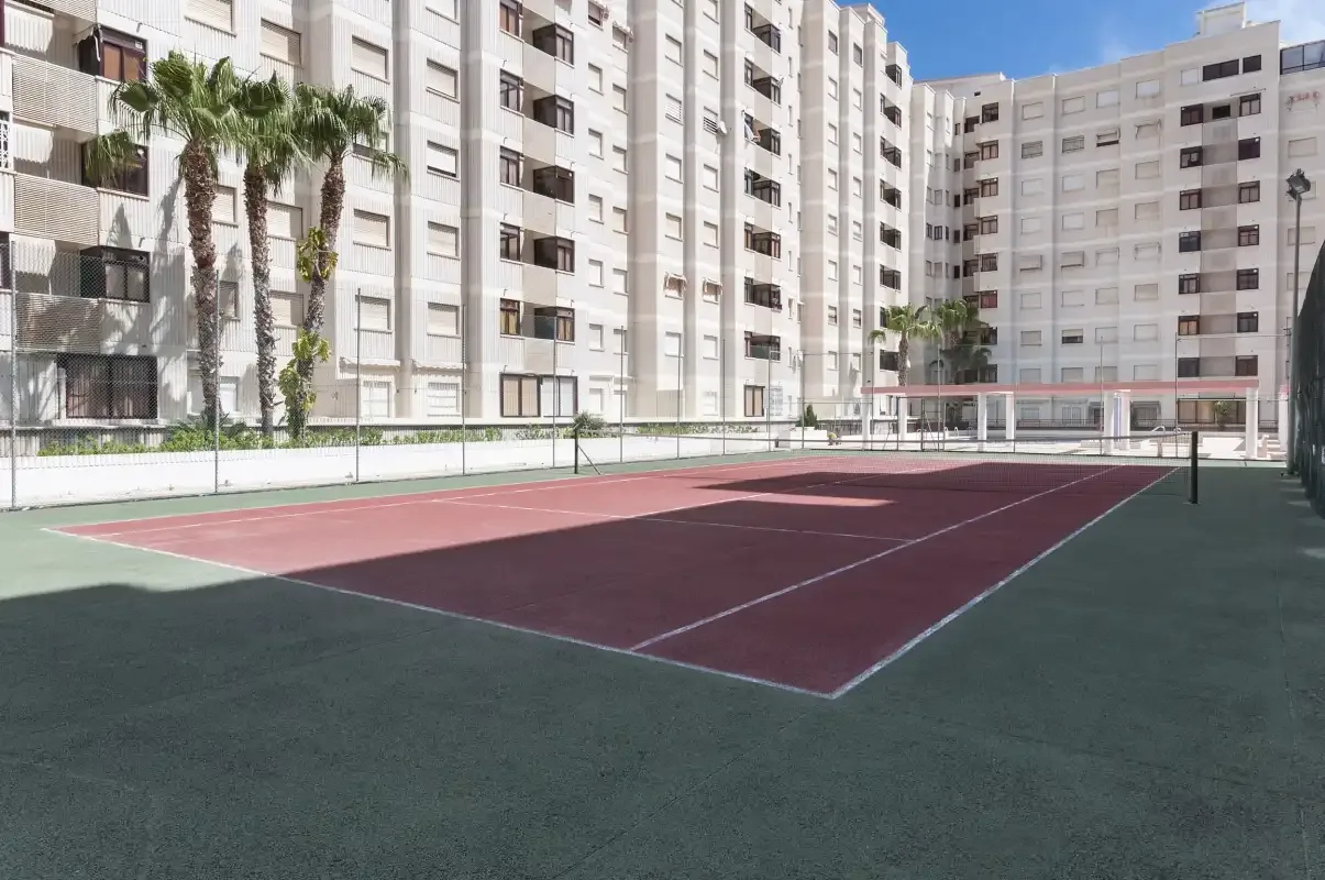 An outdoor sports court sits among tall apartment buildings.