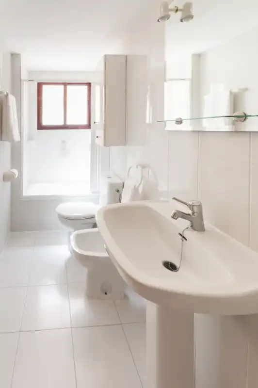 A bright bathroom with a sink, mirror, and toilet.