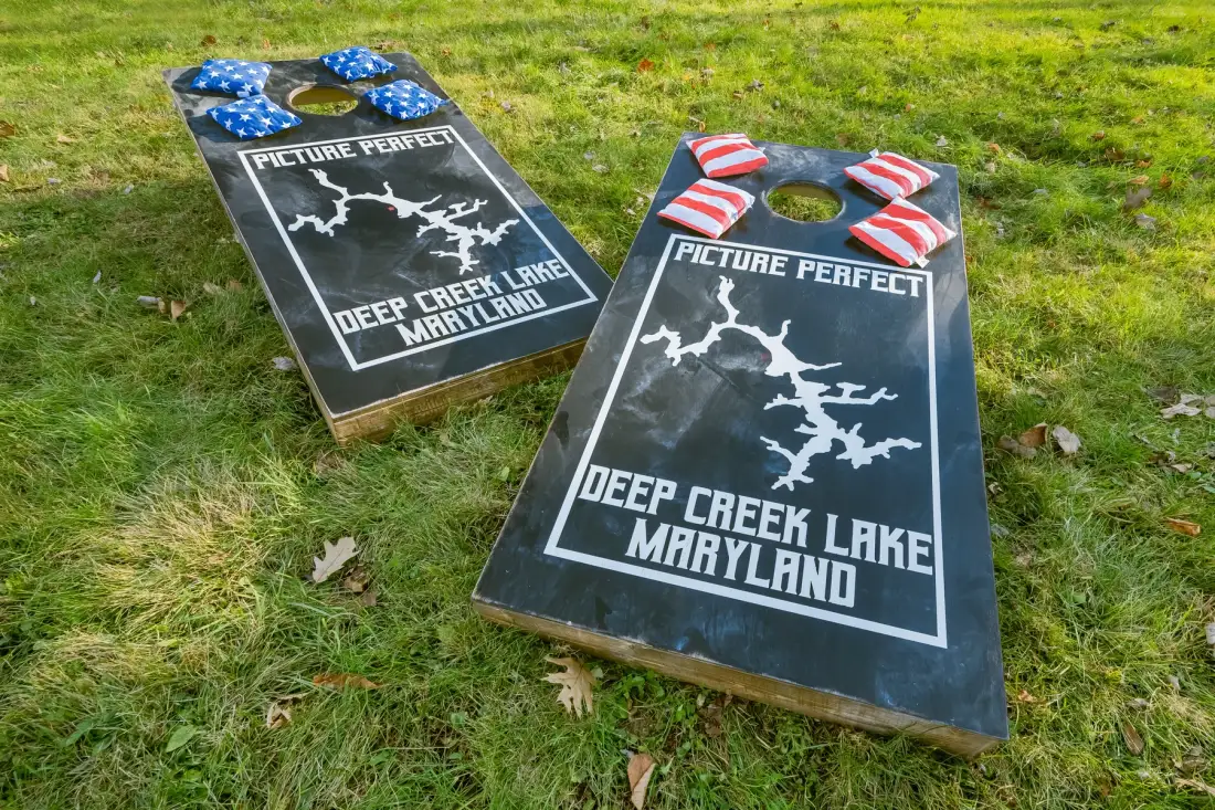 Dos tableros de cornhole están sobre el césped, decorados con diseños de Maryland.