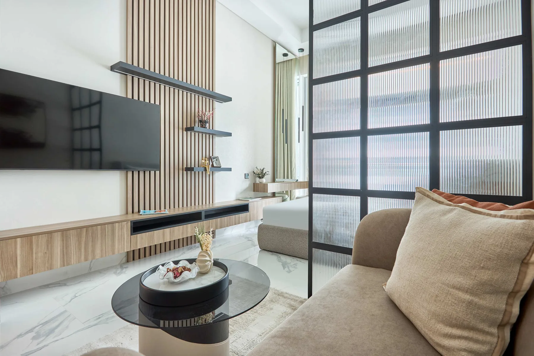 Una sala de estar moderna con asientos, un televisor y una mesa de centro de vidrio.