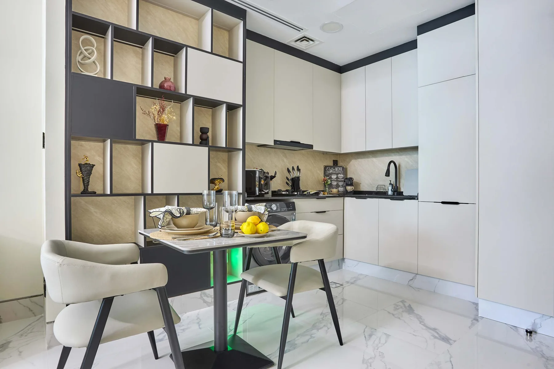 Una cocina moderna con zona de comedor, armarios blancos y una mesa.