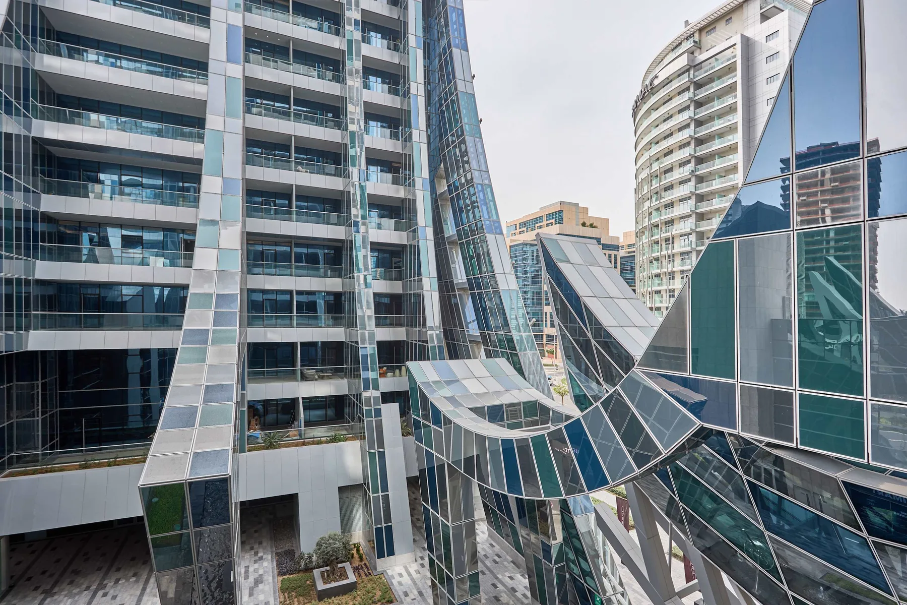 Edificios modernos de vidrio y acero rodean una fachada angular y escultórica.