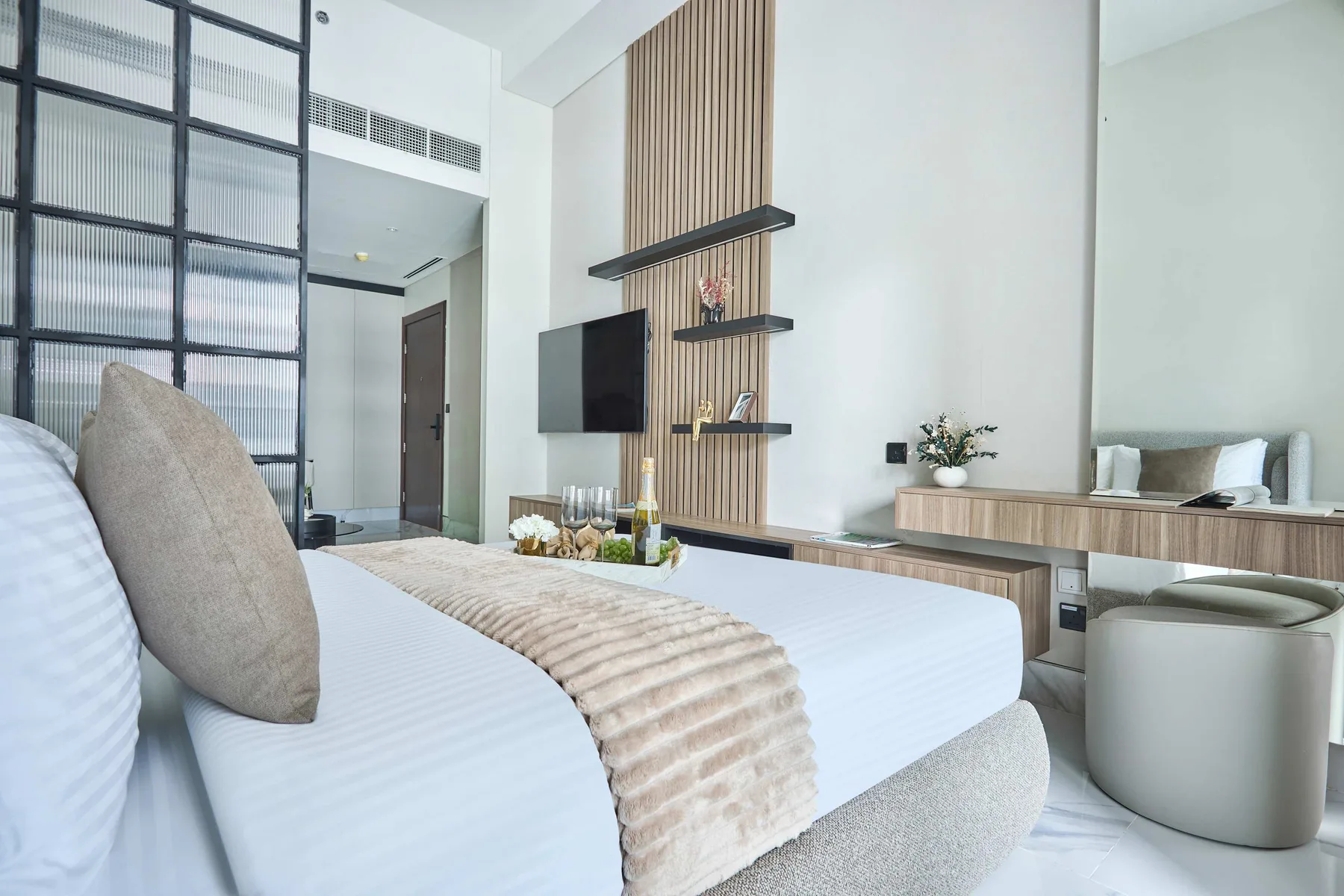 Un dormitorio luminoso con una cama, un televisor en la pared y un escritorio.