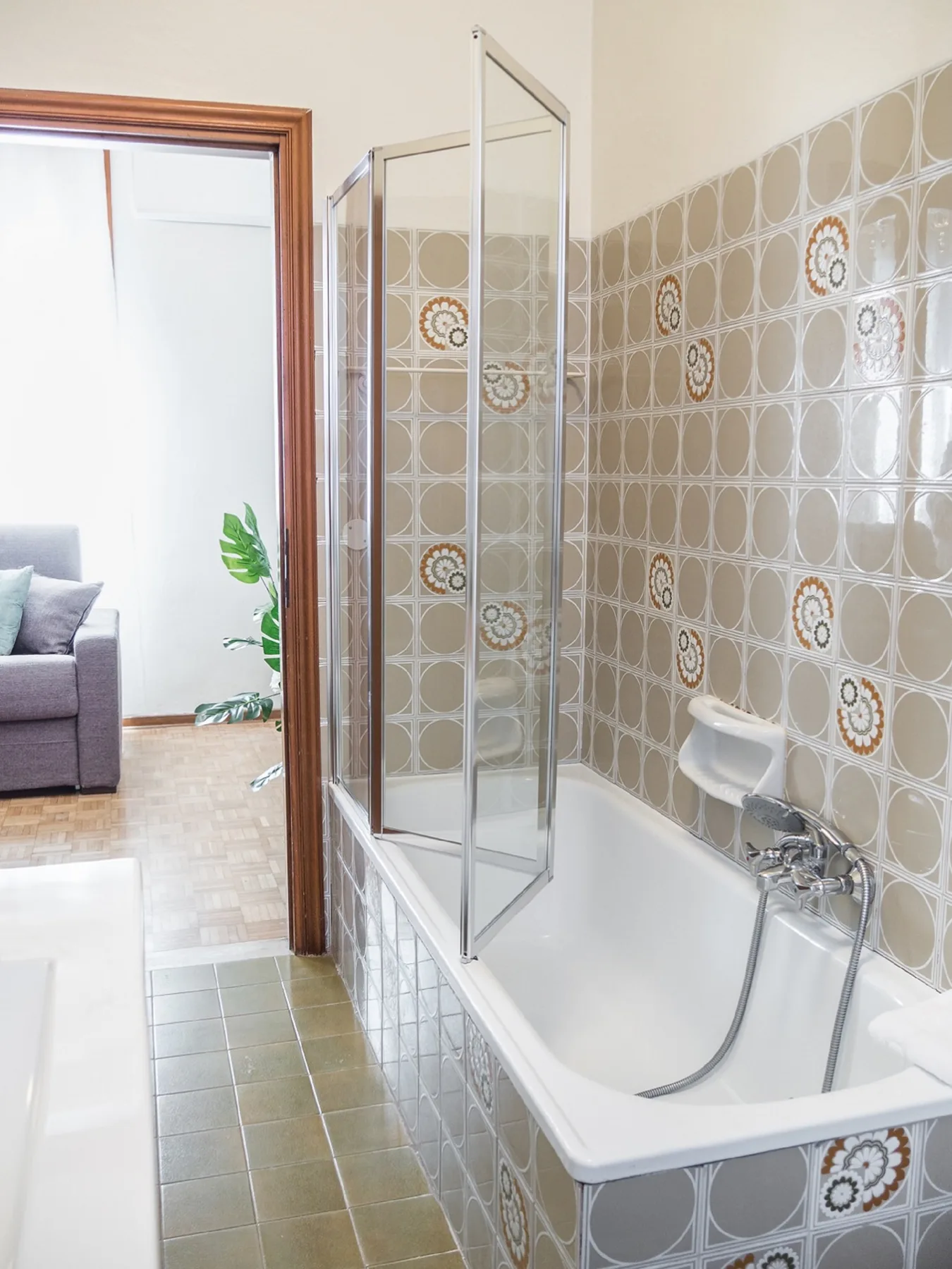 Un baño con bañera, ducha de mano y azulejos decorados en la pared.