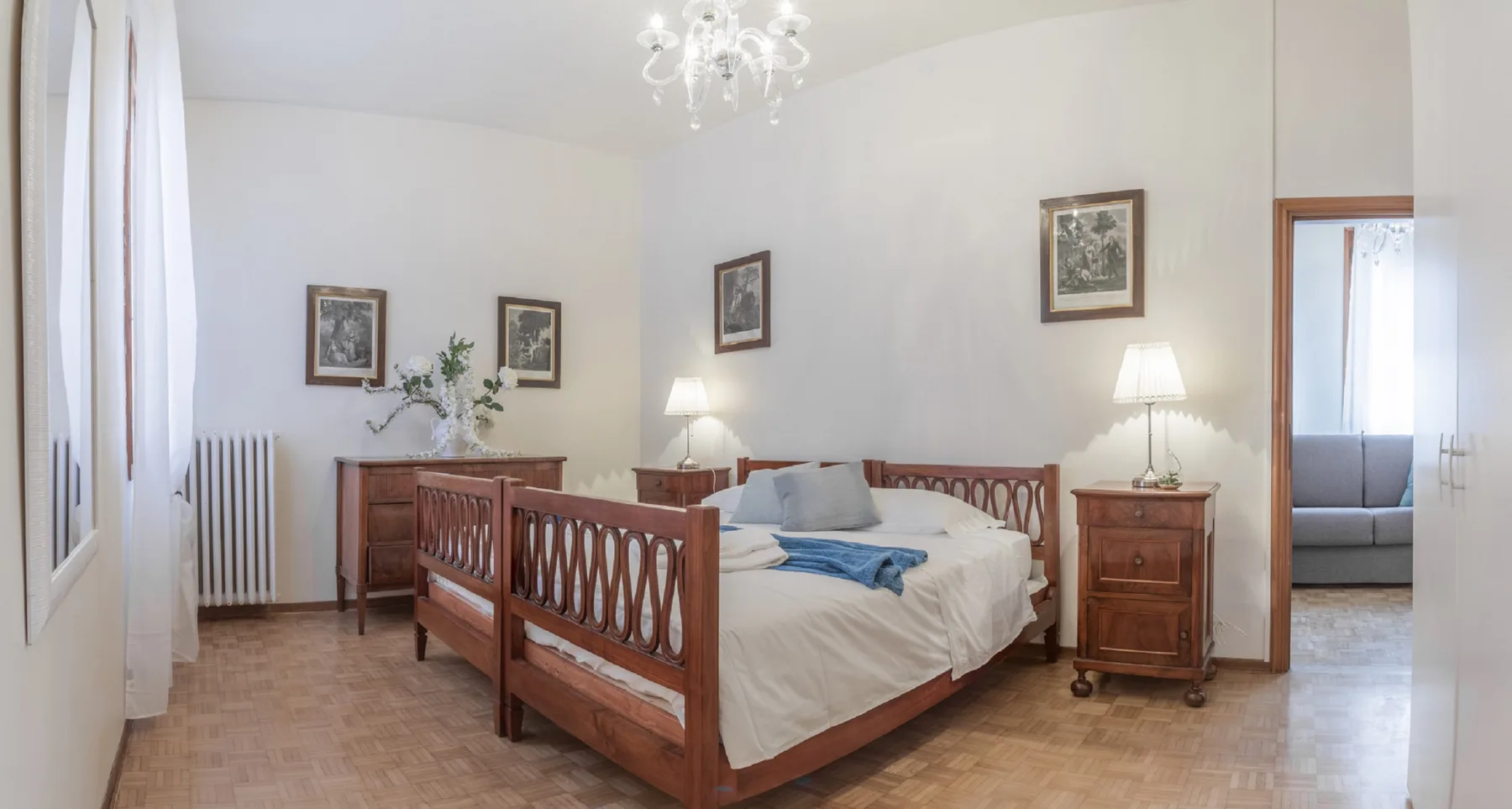 Un dormitorio con una cama de madera, mesas de noche y cuadros enmarcados.