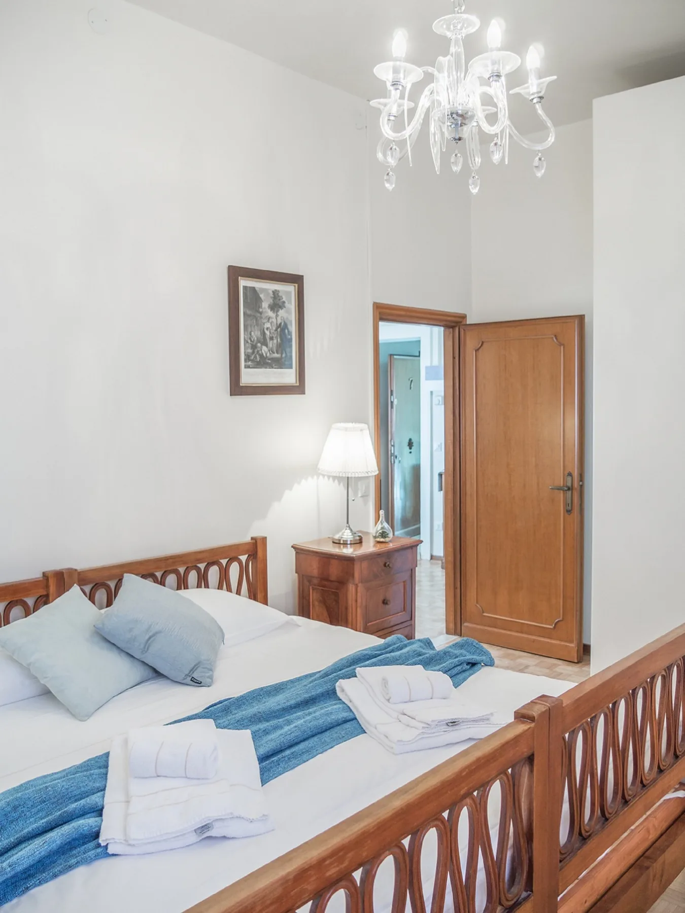 Un dormitorio con una cama de madera, ropa de cama azul y una puerta de madera.
