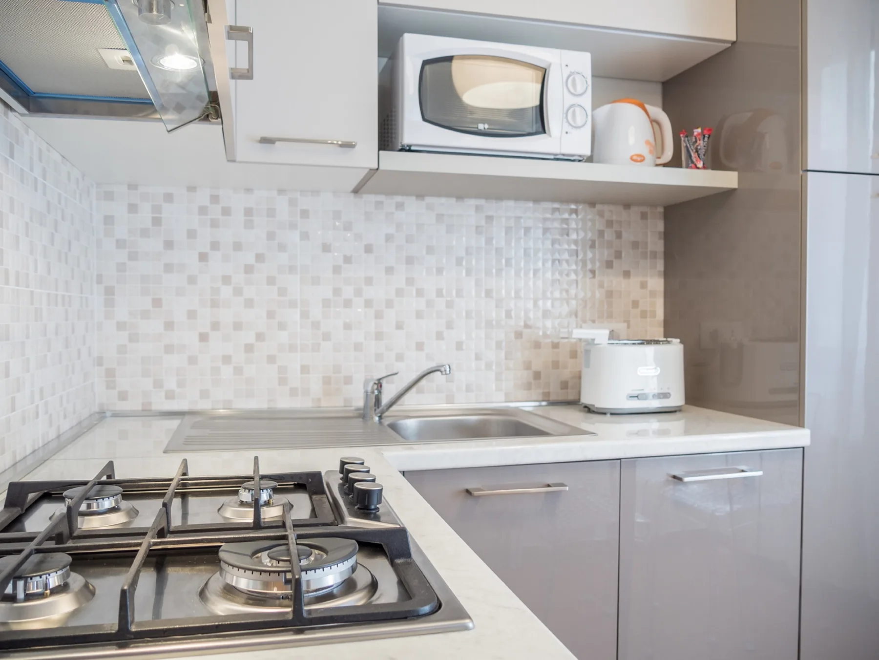 Una cocina compacta con estufa de gas, fregadero, microondas y electrodomésticos sobre la encimera.