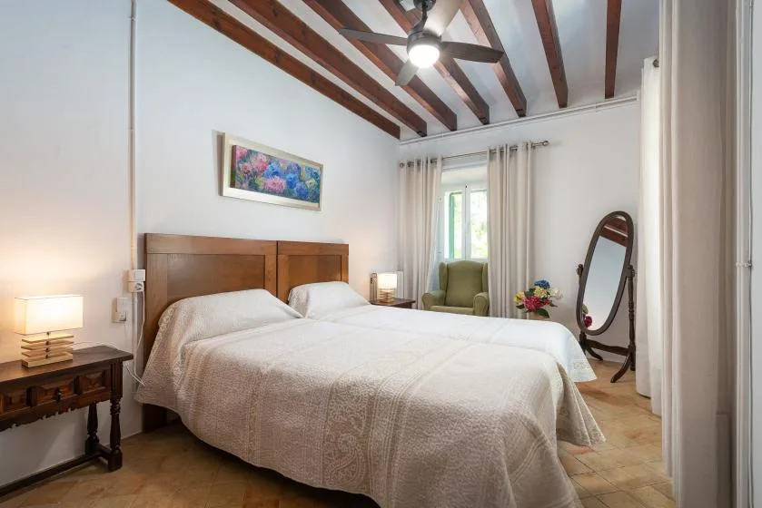 Un dormitorio con una cama doble, vigas vistas en el techo y una ventana con cortinas.