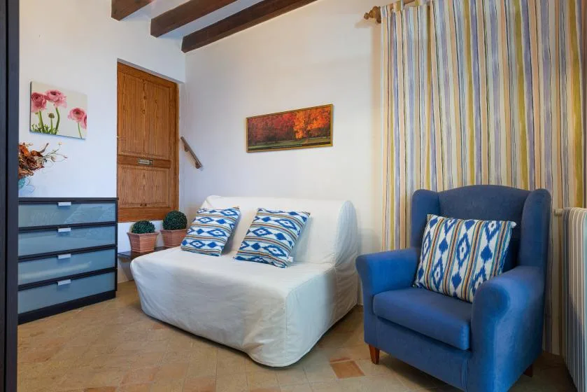 Una sala de estar con un sofá blanco y un sillón azul.