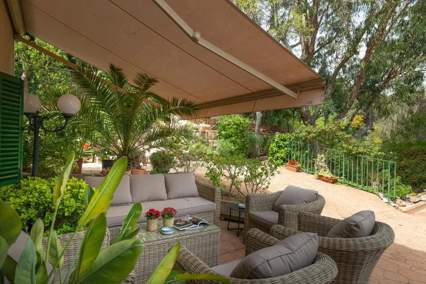 Un patio al aire libre con asientos acolchados bajo un gran toldo.