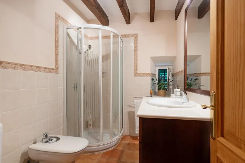 Un baño con una ducha curva de vidrio y un lavabo junto a un inodoro.