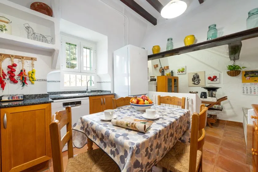 Una zona de comedor en la cocina con una mesa bajo vigas expuestas.