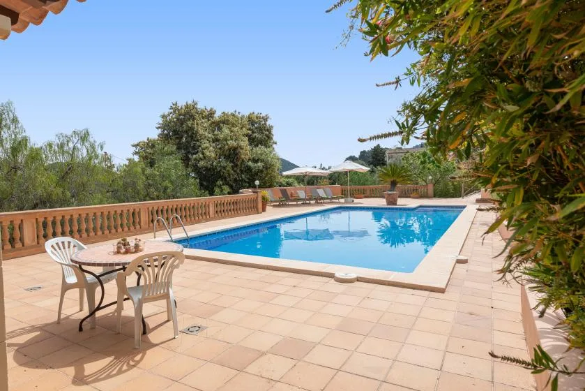 Una piscina al aire libre junto a un patio embaldosado con asientos.