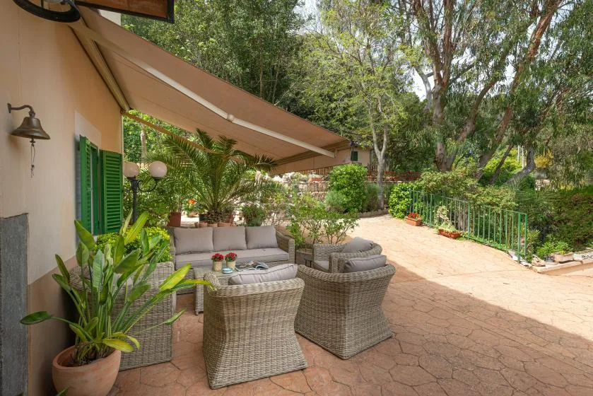 Un patio al aire libre con asientos acolchados está junto a un sendero de jardín.