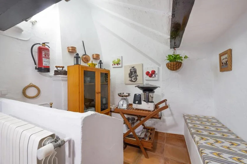 Un pequeño comedor con una mesa de madera, asientos y un armario con puertas de vidrio.