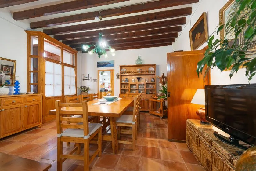 Un comedor con una mesa y sillas de madera bajo vigas de techo expuestas.