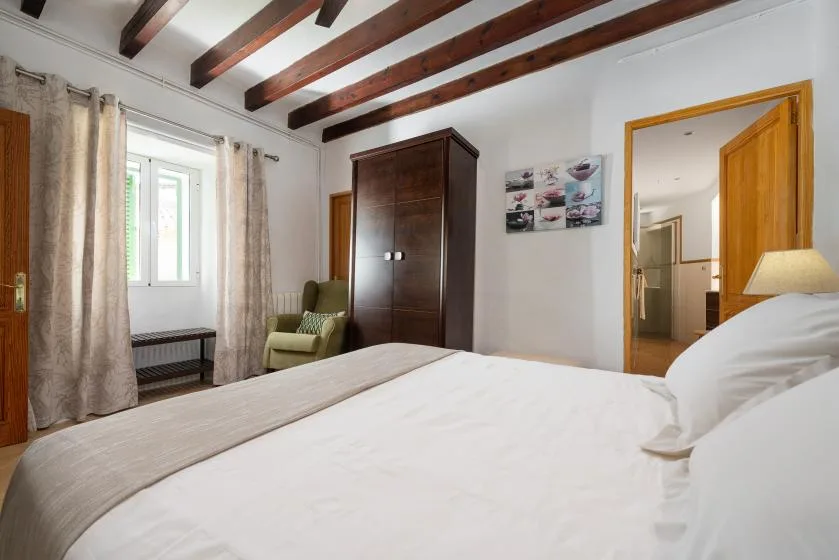 Un dormitorio con una cama grande, un armario y una ventana con cortinas.