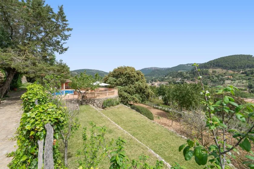 Un jardín ajardinado contempla colinas verdes bajo un cielo azul despejado.