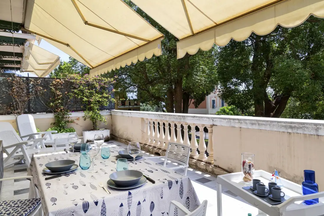Comedor al aire libre con mesas bajo grandes toldos de color crema.