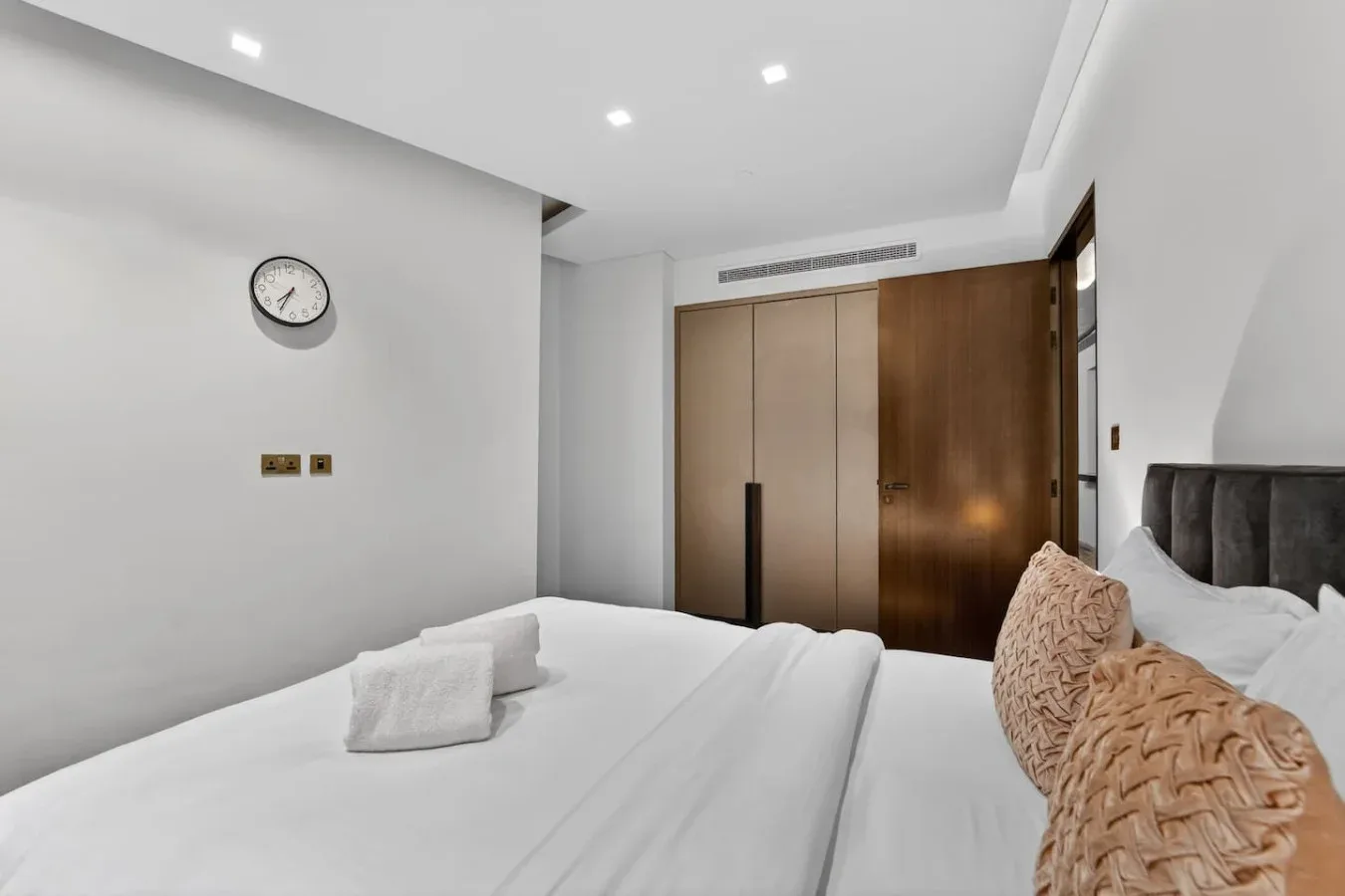A bright bedroom with a neatly made bed and built-in wardrobes.