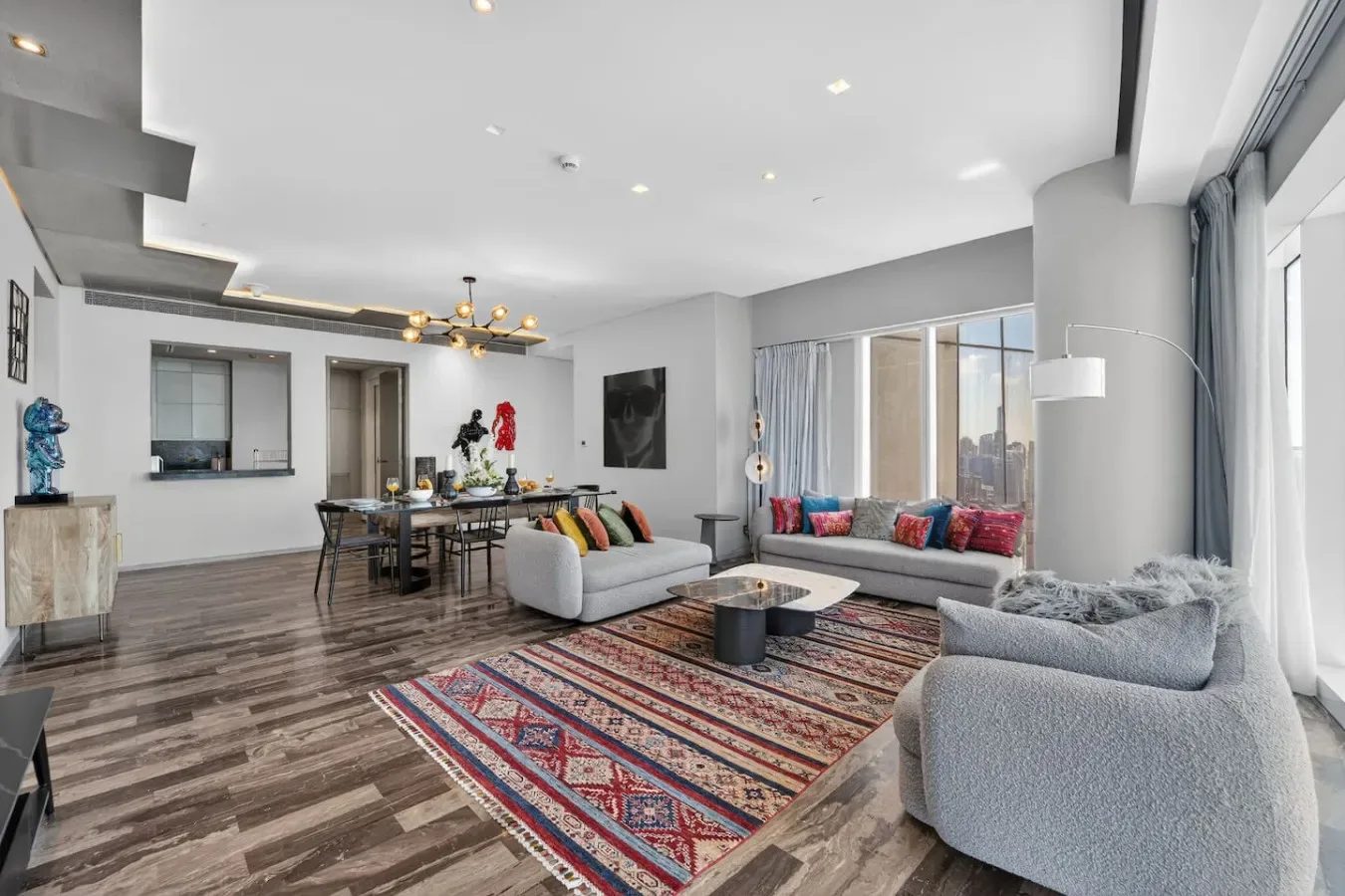 A bright living room with seating around a coffee table and a dining area.