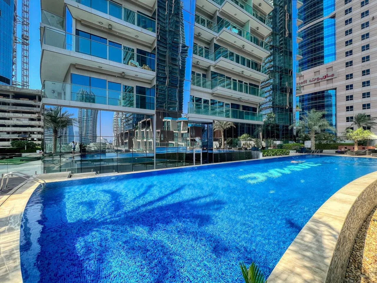 A swimming pool sits beside modern high-rise buildings.