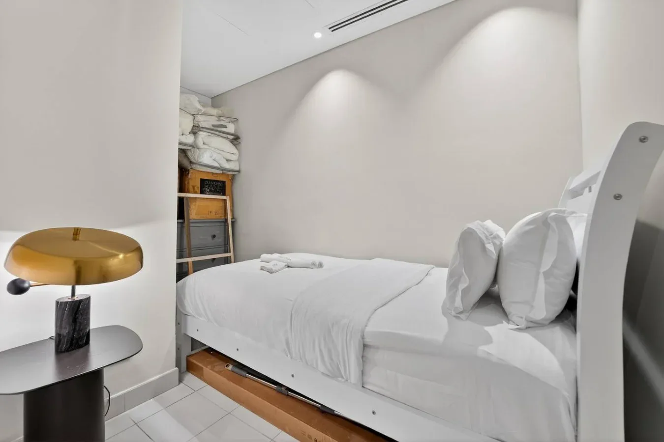 A bright bedroom with a neatly made bed and a small bedside table.