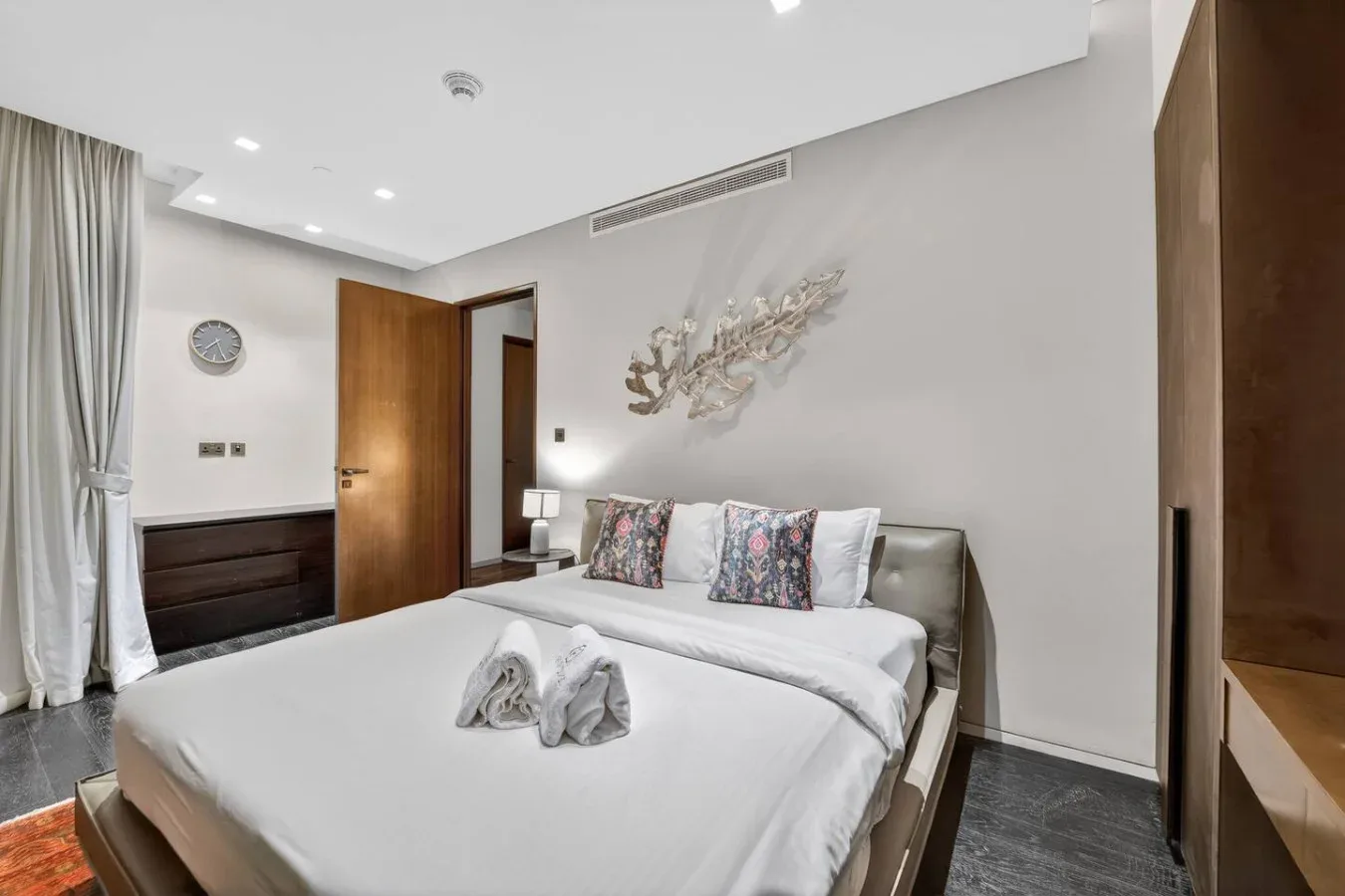 A bedroom with a neatly made bed and folded towels.