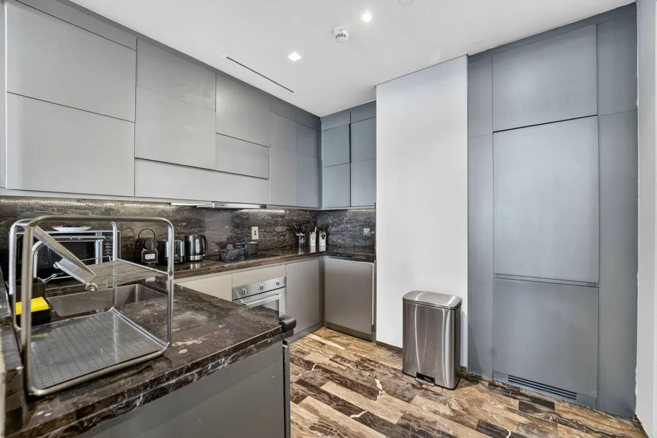 A modern kitchen with dark countertops and light cabinetry.