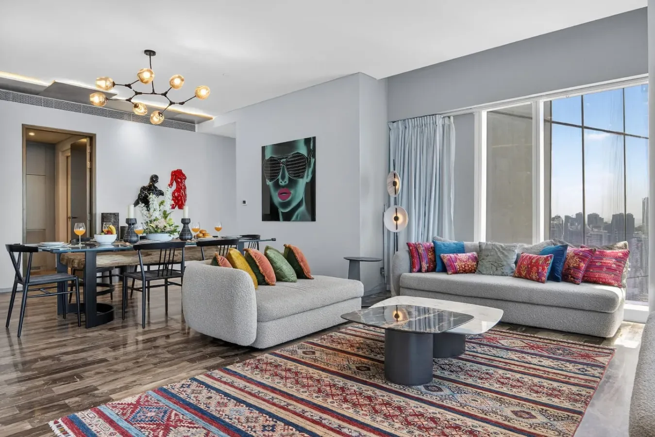 A bright living room with seating around a coffee table beside large windows.