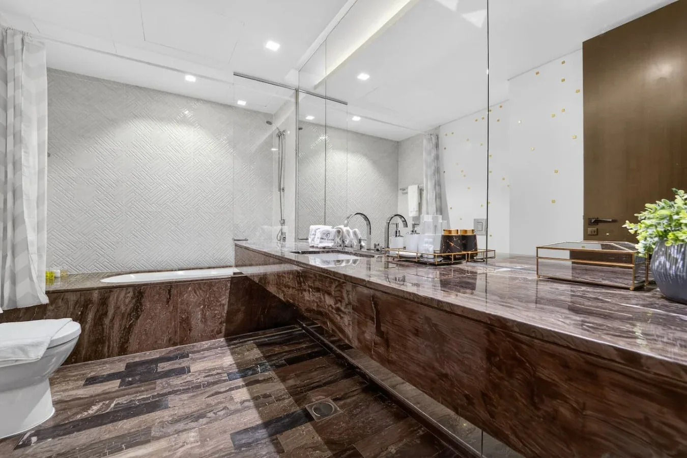 A spacious bathroom with a bathtub, glass shower area, and long vanity counter.