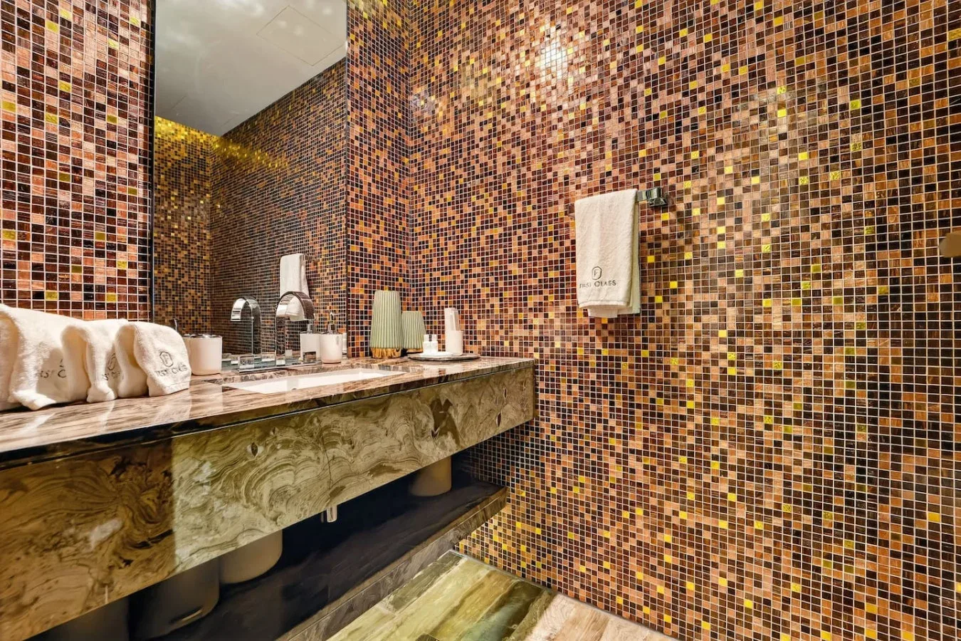 A tiled bathroom vanity with a wide countertop and folded towels.