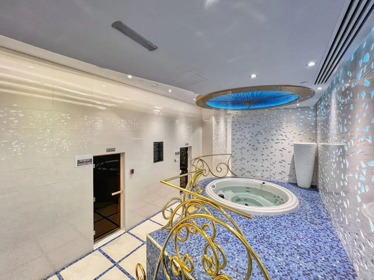 A spa room features a round whirlpool beside decorative gold railings.